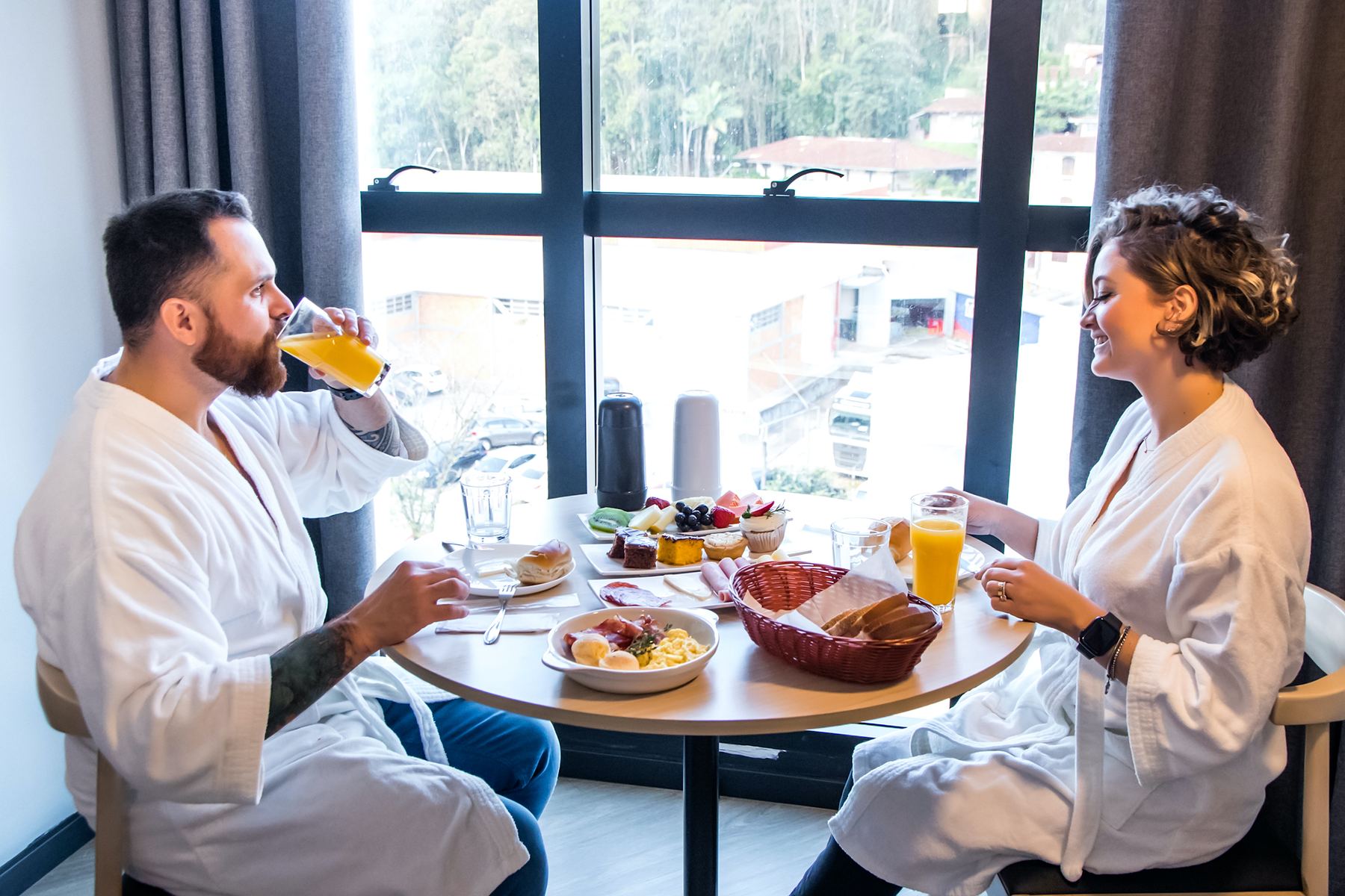 Casal de roupão tomando café da manhã no quarto