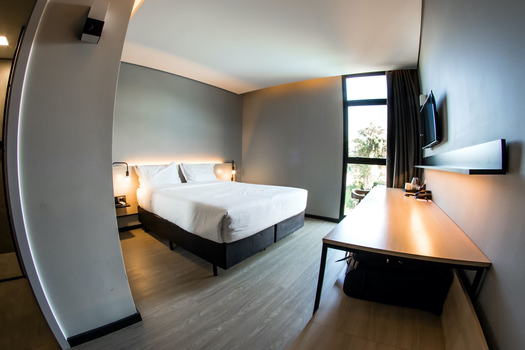 Quarto do Naalt Hotel com janela do chão ao teto e mesa de trabalho